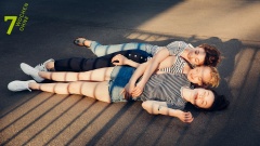 Drei Frauen liegen auf einer Straße und umarmen sich.