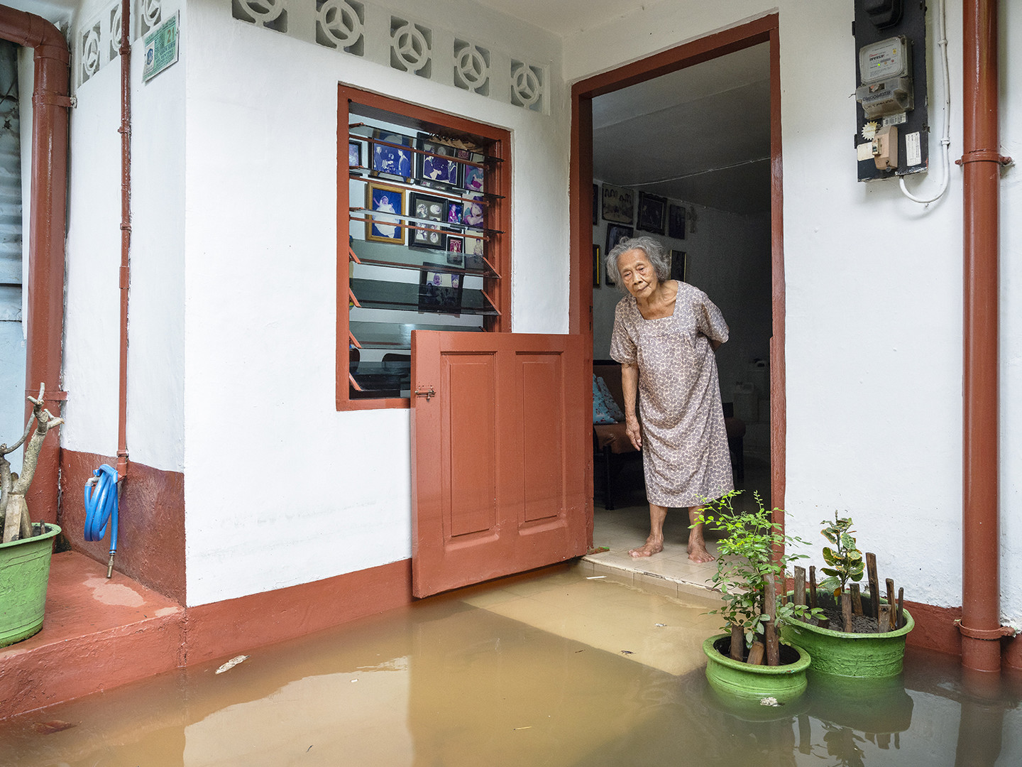 Indonesierin schaut auf Überflutung vor ihrem Haus