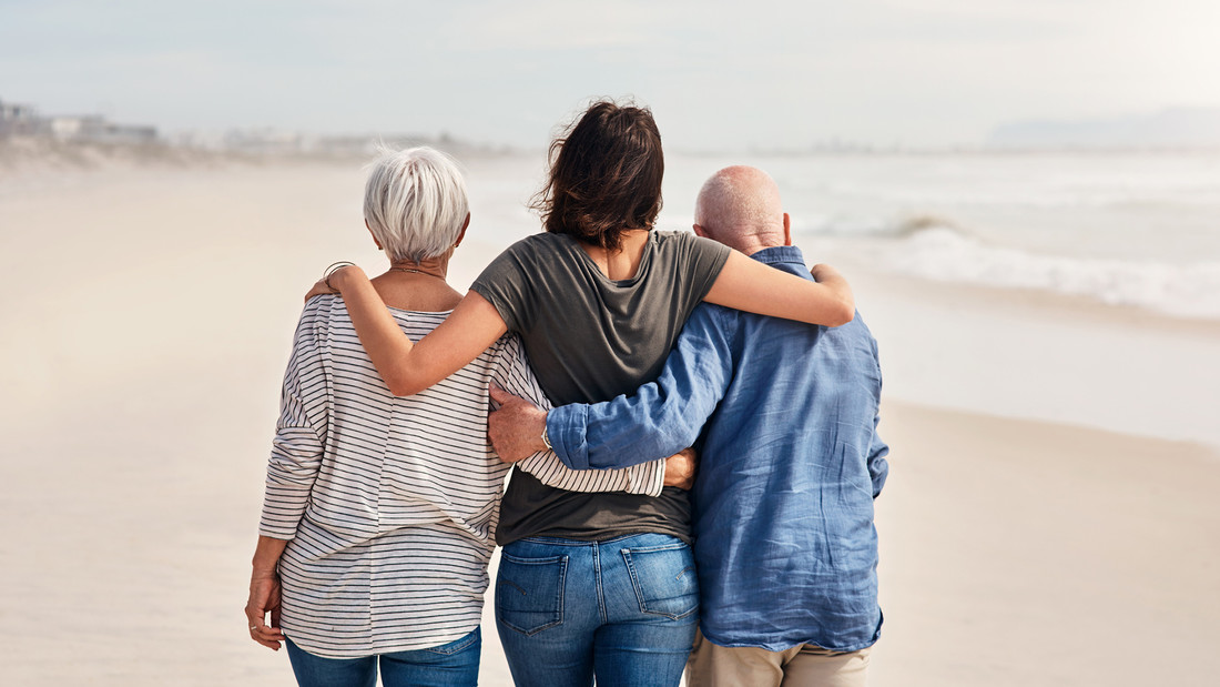 Tochter geht mit Vater und Mutter am Strand entlang