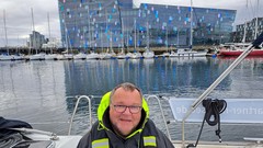 Portait eines Mannes auf einem Segelbot im Hafen mit Hafen Skyline.