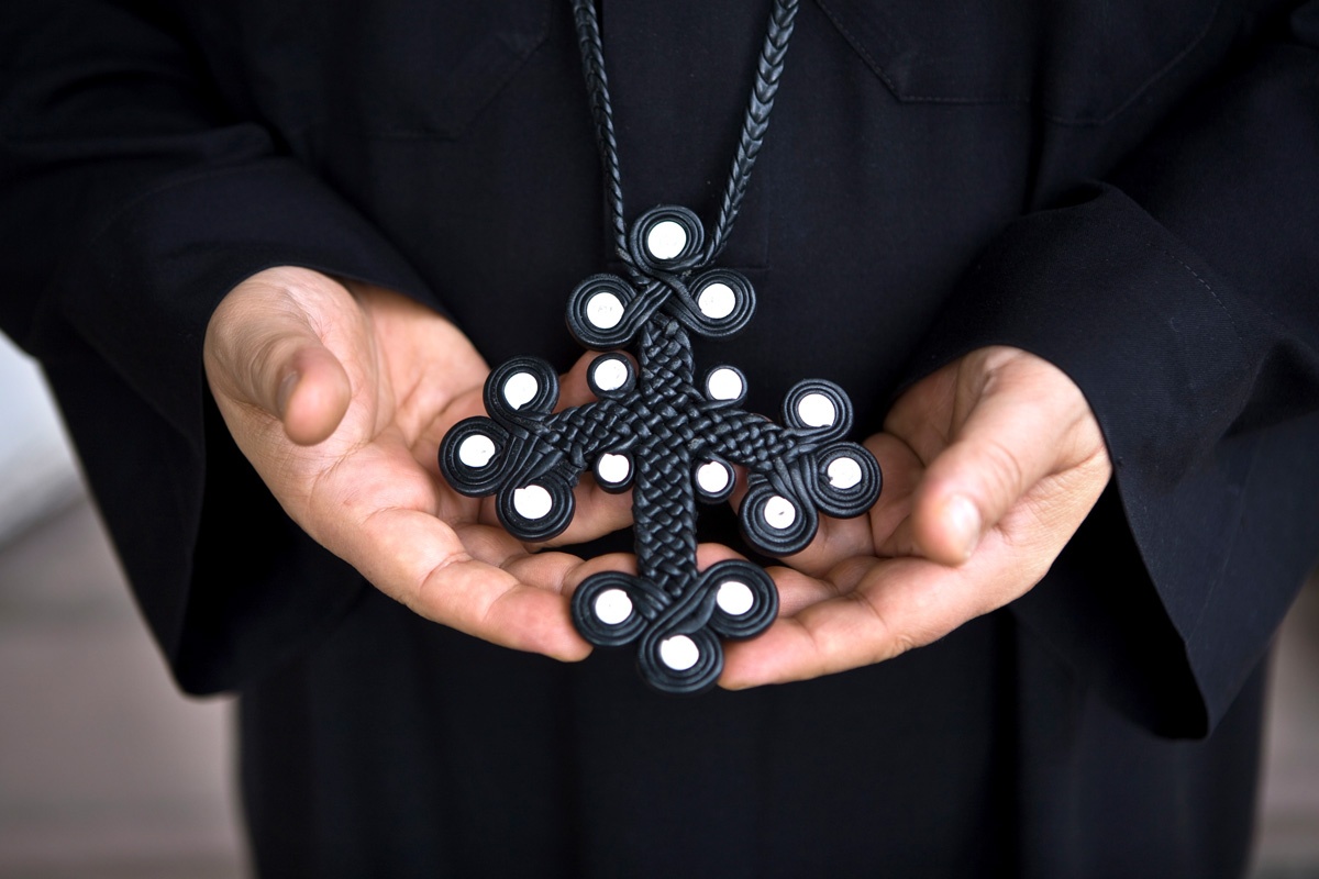 Ein aus Leder geflochtenes, schwarzes Kreuz mit zwölf Kreisen an den äußeren Enden und vier Kreisen in der Mitte.