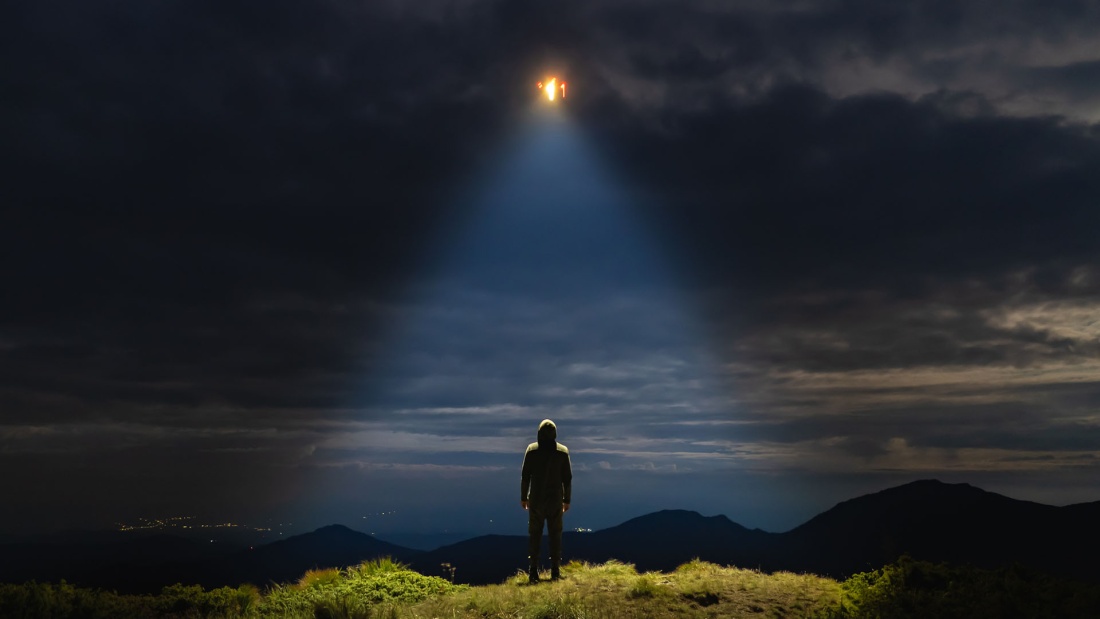 Ufo leuchtet über einem Mensch am Himmel