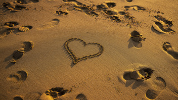Fußspuren und Herz im Sand