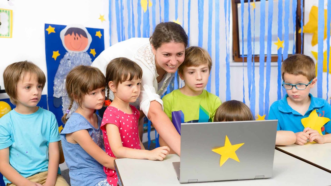 Erzieherin mit Kindegartenkindern am Laptop