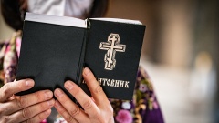 Gläubige hält ein Gesangbuch bei Ukrainisch-Orthodoxem Gottesdienst