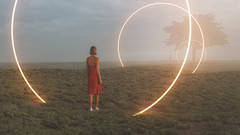 Frau steht in einer surrealen Landschaft mit Leuchtkreisen