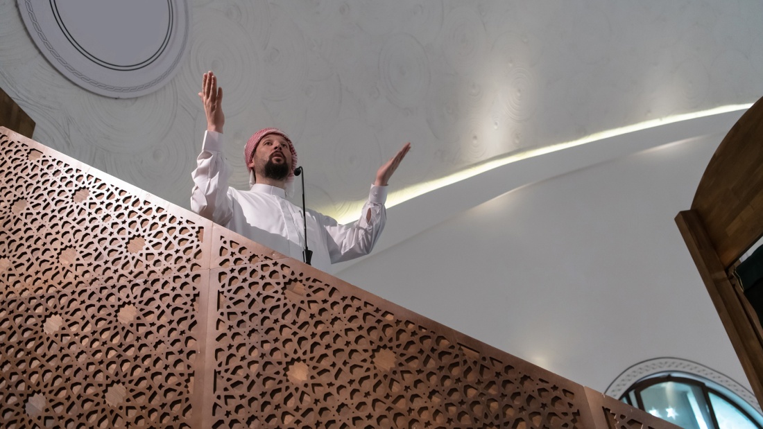 Imam steht auf einer Empore und spricht