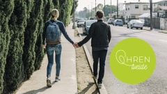 zwei Personen laufen Händchen halten auf einer leeren Straße