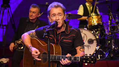 Peter Maffay sitzt mit Gitarre auf Bühne