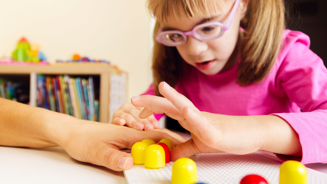 Sehbehindertes Mädchen spielt mit Mosaik-Peg-Board 