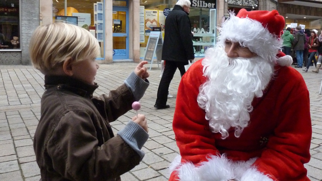 Nikolaus spricht mit Kind in der Fußgänger Zone.