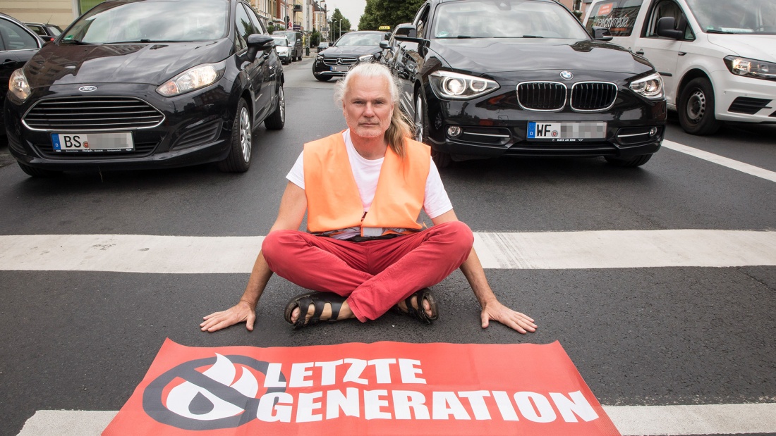 Aktivist Edmund Schultz sitzt auf der Straße vor Autos