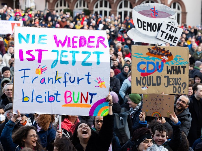Schilder werden bei der Kundgebung "Frankfurt steht auf für Demokratie" hochgehalten. "Nie wieder ist jetzt Frankfurt bleibt Bunt" steht auf einem der Schilder, auf einem der anderen "CDU what would Jesus do?" 