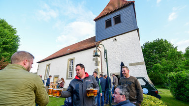 Männer mit Bierkrügen vor der Kneipenkirche