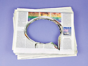 Stapel Zeitungen. In der Mitte ist ein Loch in der Form einer Sprechblase herausgerissen 