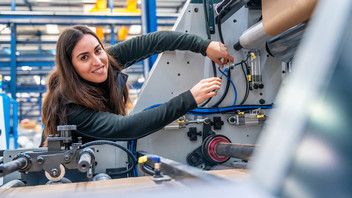 Ingenieurin repariert eine CNC-Maschine in einer modernen Logistikfabrik