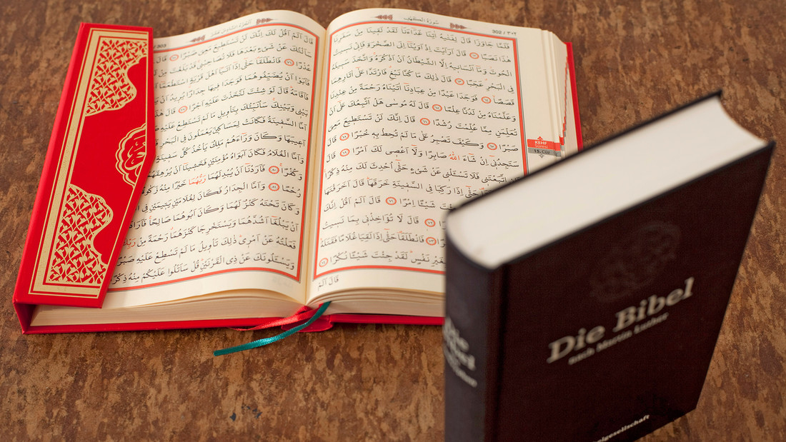 Ein aufgeschlagener Koran liegt neben einer Bibel .
