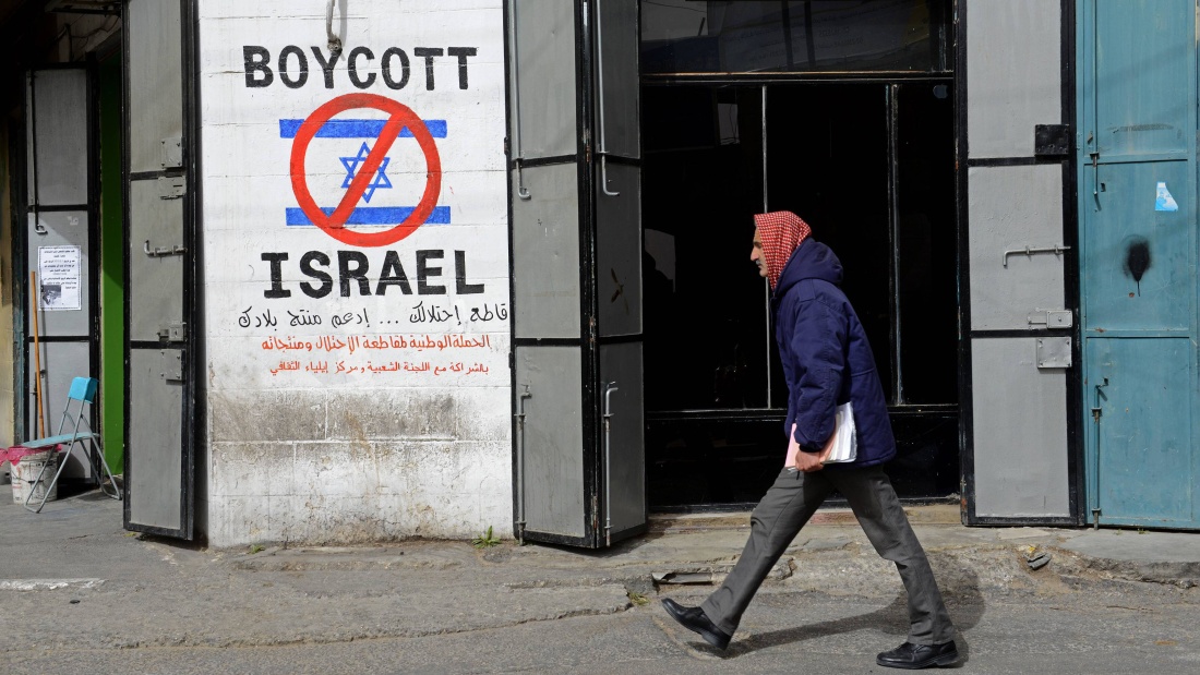 Ein Palästinenser geht an einem Graffiti mit der Aufschrift "Boykottiert Israel" am Eingang zum Flüchtlingslager Beit Jibrin in Bethlehem, Westjordanland, vorbei