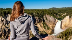 Frau blickt auf einen Wasserfall im Yellowstone National Park in den USA.