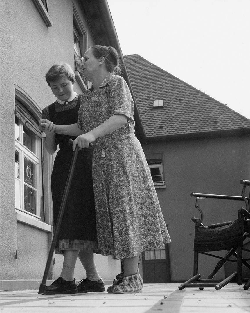 Junge Frau hilft älterer Frau mit Stock