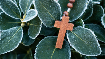 Holzkreuz auf winterlichen Blättern