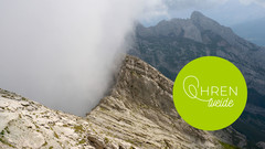 Im hohen Gebirge steigt eine Wolkenwand am Berg hinauf