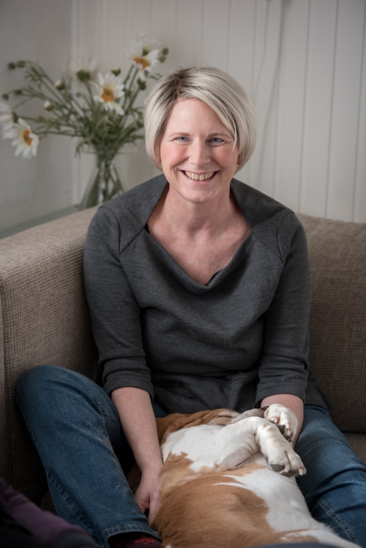 Portrait von Sabine Dinkel mit Hund auf einem Sofa