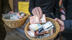 Spendenkorb mit Geld vor einer Kirche 