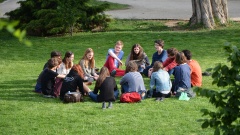 Gruppe Jugendlicher sitzt im Kreis auf einer Wiese