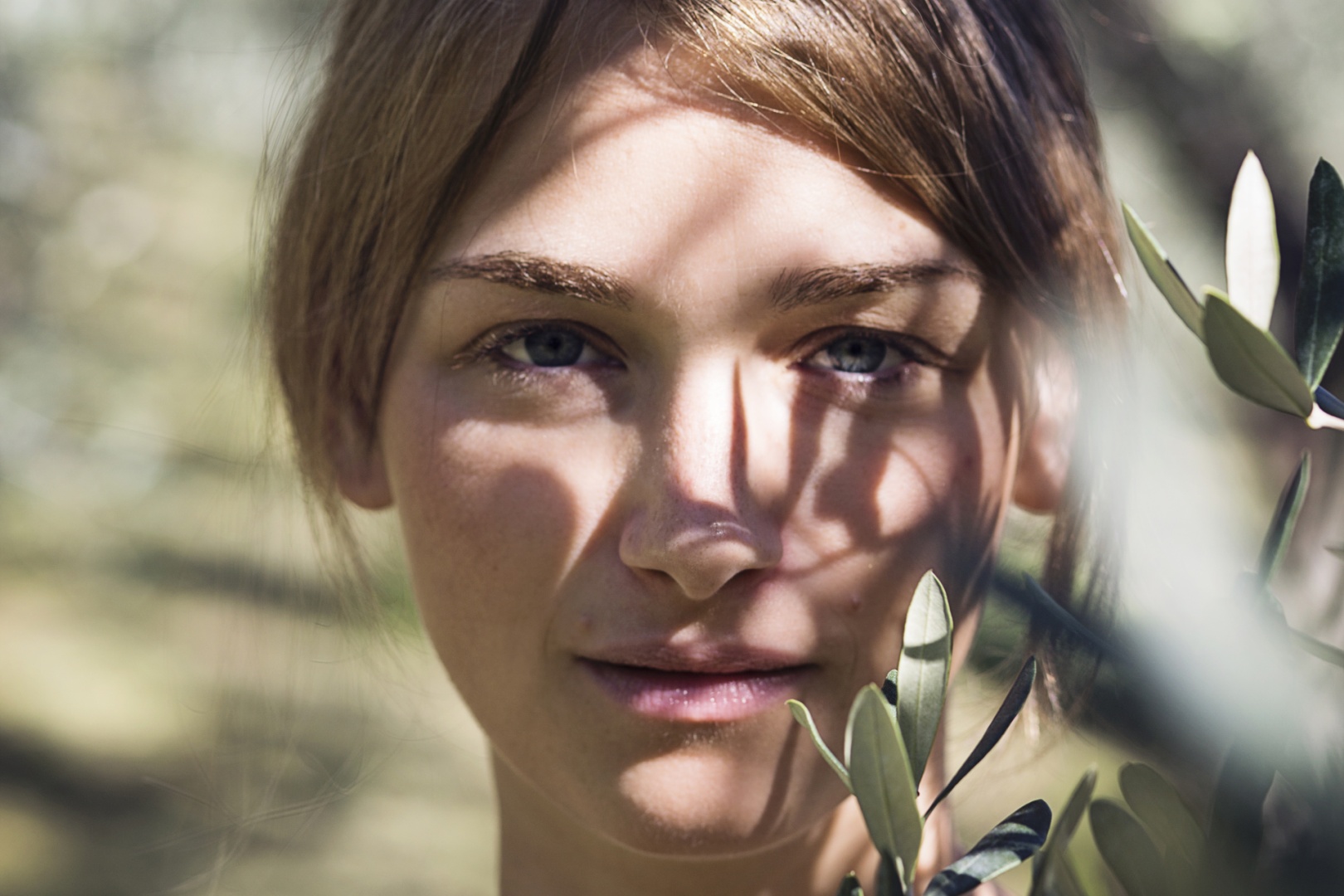 Portrait einer Frau mit Ölbaumblätter vorm Gesicht