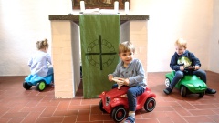 Kinder fahren im Bobbycar um den Altar