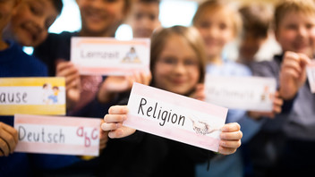 Kinder in der Unschärfe halten kleine Schilder mit Religion beschrieben hoch.