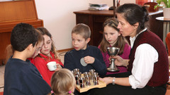 Eine Frau erklärt Kindern das Abendmahlgeschirr.