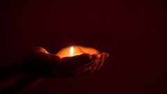 Brennende Kerze in einer Hand gehalten