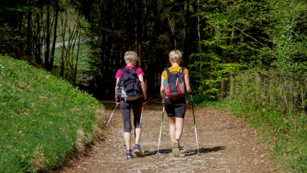 Zwei Frauen gehen mit Walkingstöcken durch den Wald