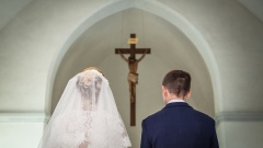 Brautpaar in Kirche mit Kreuz an der Wand