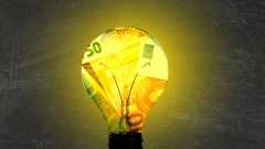Glühbirne mit Geldscheinen als symbol für Energiekosten