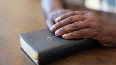 Betende, dunkelhäutige Hände auf einer Bibel