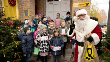 Vor der Weihnachtspostfiliale Himmelpfort steht der Weihnachtsmann umgeben von Kindern