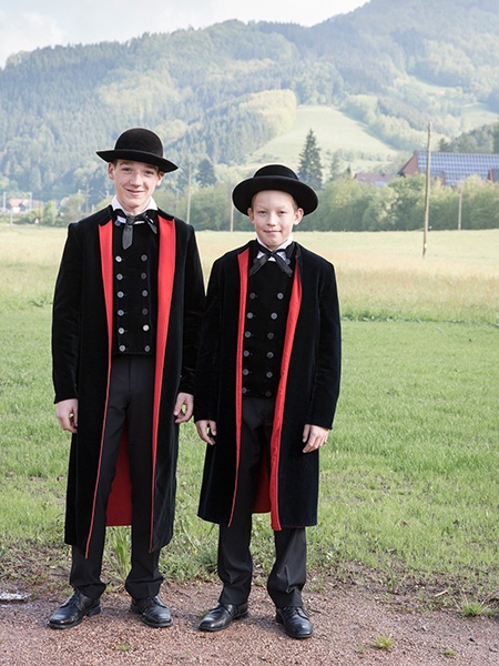 Zwei Jungen in der Gutacher Tracht mit geknöpften Westen, schwarzen Hüten und Mänteln mit roten Aufschlägen