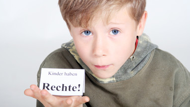 Ein Junge hält ein Schild auf seiner Hand auf dem steht: Kinder haben Rechte!