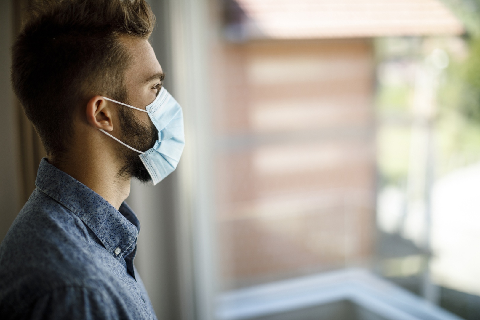 Mann mit Mundschutz am Fenster