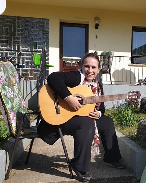 Pfarrerin Anneke Peereboom mit Gitarre zur Andacht vor einem Haus