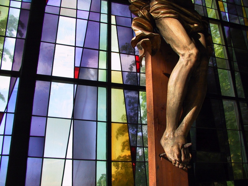 Kruzifix vor farbigem Kirchenfenster