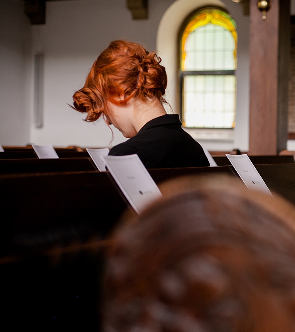 Frau in Kirchenbank. Sie sieht nach unten