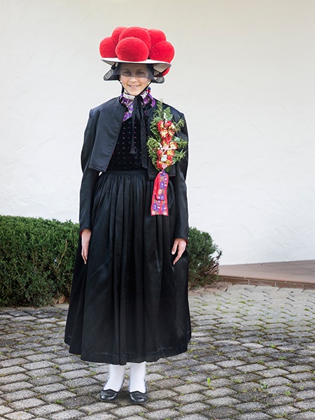 Junge Frau in Gutacher Tracht mit rotem Bollenhut und Schmuckband