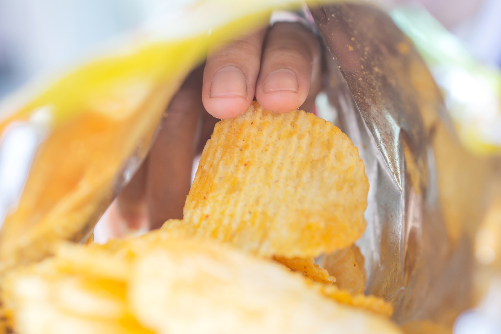 Eine Hand greift in eine Tüt mit Chips