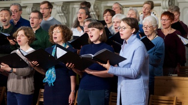 Eine Gruppe von Menschen singt in einem Chor in einer Kirche ohne Masken.
