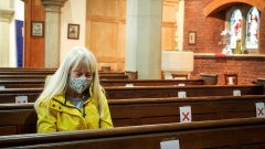 Frau sitzt in leerer Kirche in Corona-Zeiten