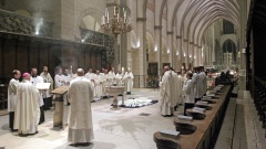 Blick in eine große, weiße Kirche mit mehreren Männern und Jungs in weißen Gewändern, die um Kerzen auf dem Boden herumstehen